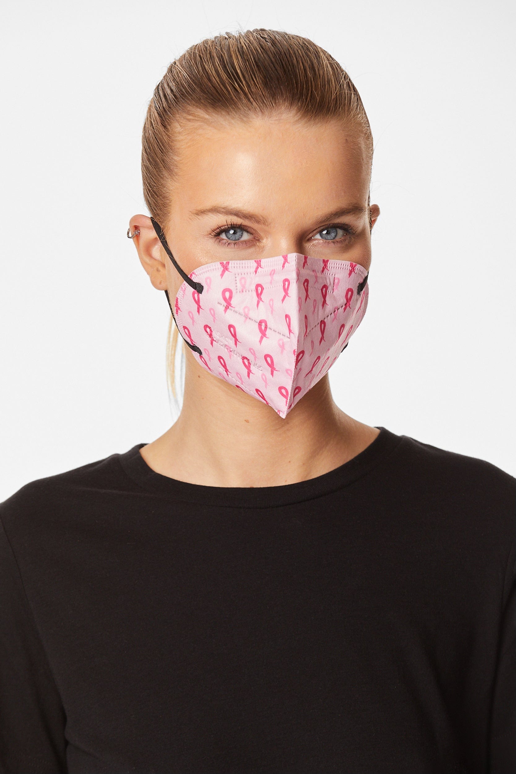 Woman wearing stylish pink breast cancer awareness ribbon printed KN95 face mask, with high quality breathable fabric. 