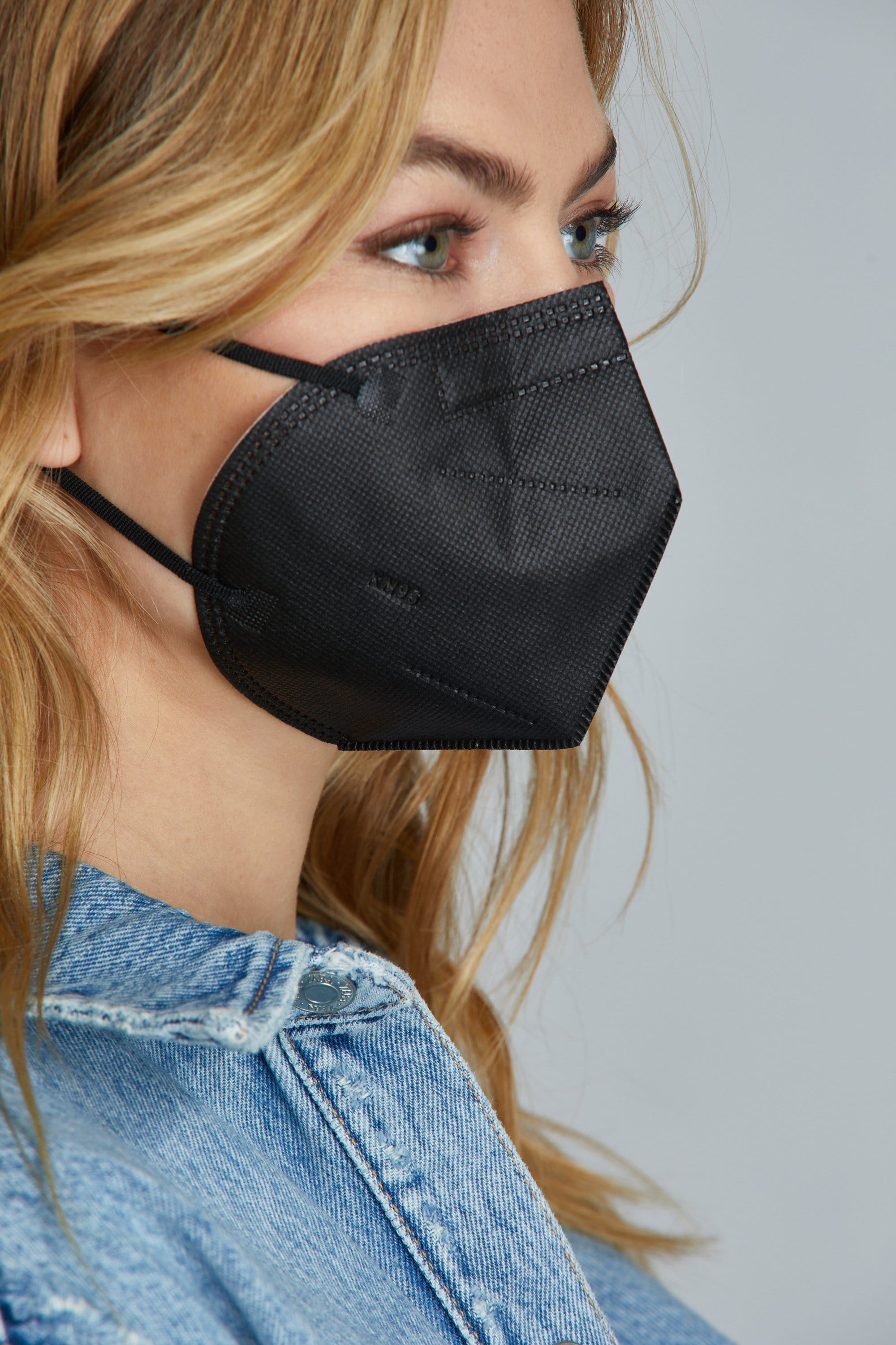 Side view of woman wearing Black KN95 face mask, with high quality breathable fabric. 