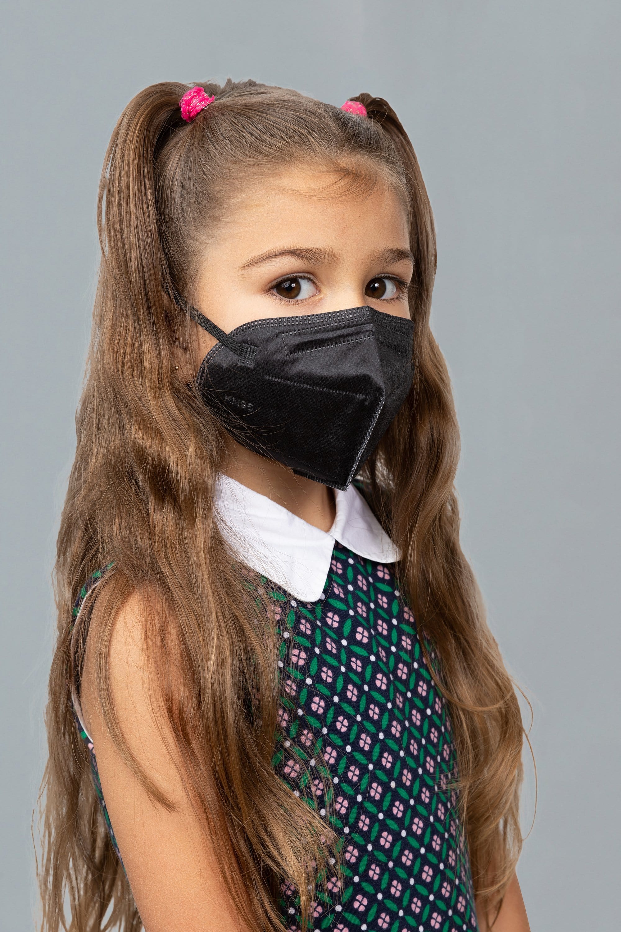 Child wearing stylish kid sized Black KN95 face mask, with high quality breathable fabric. 