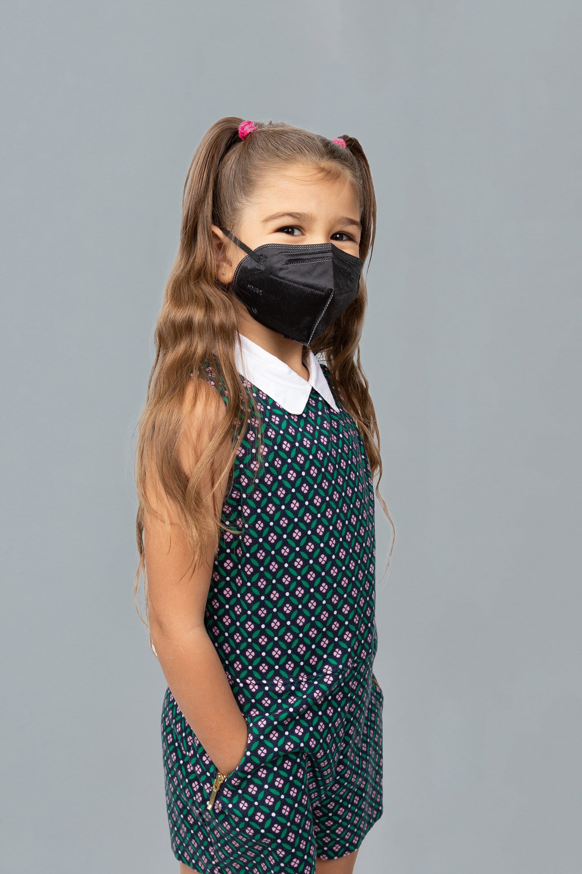 Child wearing stylish kid sized Black KN95 face mask, with high quality breathable fabric. 